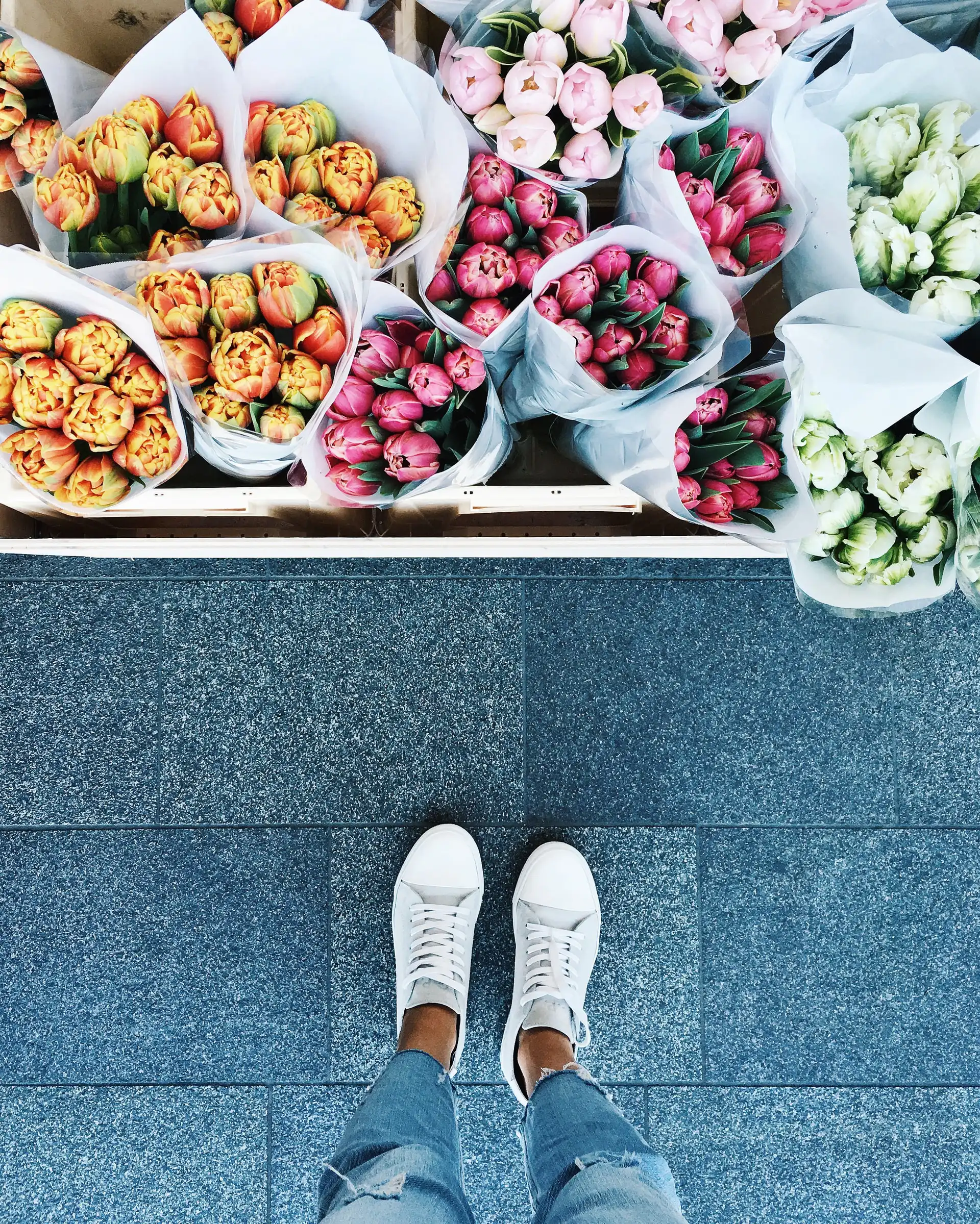 top view of white shoes near bouquets of flowers